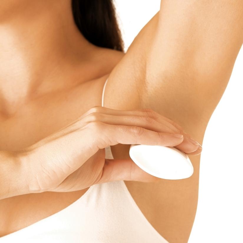Woman applying deodorant on her left underarm