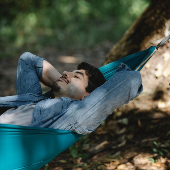 Guy sleeping peacefully in a blue hammock